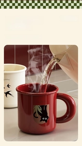 Detail of pouring hot water into a red ceramic cat mug with heat-resistant smooth finish