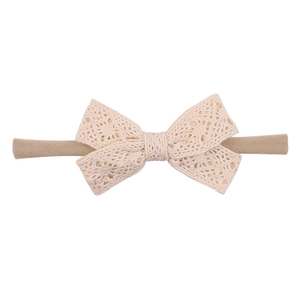 Detailed macro view of beige lace bow and elastic tan fabric headband for infants