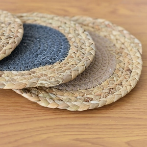 Detail of woven straw round placemat showing handmade corn husk texture and braided edge