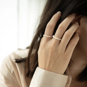 Detail of minimalist 925 silver stretch rings with small white baroque pearls on a hand