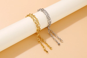 Close-up of interlocking chain link necklaces in gold and silver finish on display