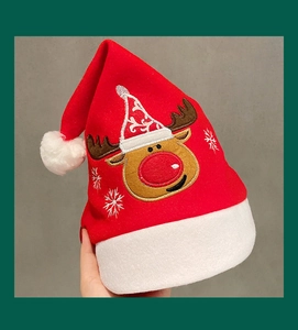 Close-up of red plush Christmas hat featuring white fur trim and detailed elk embroidery