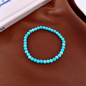 Detail view of turquoise round bead bracelet with blue stones on a brown textured fabric