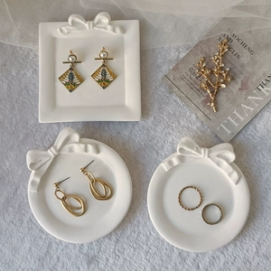Flat lay of vintage pearl earrings and gold rings on bow-accented ceramic jewelry trays