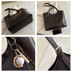 Detail view of large brown leather tote bag with baseball charm and golden hardware