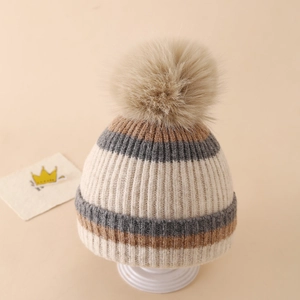 Close-up of winter knit hat featuring a fluffy faux fur pompom and ribbed stripe texture