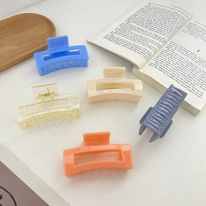 Hollow rectangular hair claws in assorted pastel colors displayed on a wooden tray