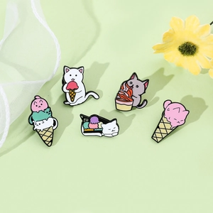 Flat lay of five cute enamel cat pins with ice cream themes on a soft green background