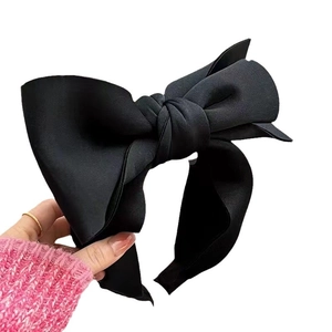 Chic black oversized fabric bow headband held against a clean white background