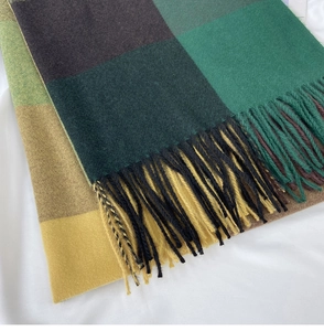 Close-up of soft plaid scarf fabric with tassels in forest green, coffee, and warm yellow