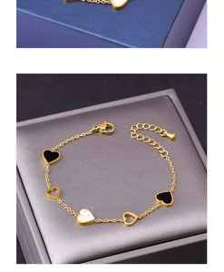 Detail of titanium heart bracelet with black and white shell inlays on golden chain
