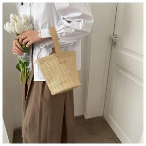Detail showing the textured woven straw bucket bag with a single handle for summer