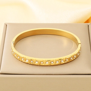 Detail of 18K gold-plated bangle with geometric texture and sparkling inlaid zircons