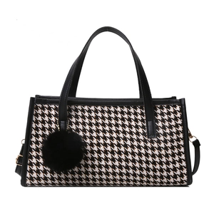 Elegant houndstooth tote bag with black leather trim and decorative fur pompom