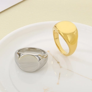 Gros plan de bagues chevalières polies plaquées or 18 carats et argent sur un plat en céramique