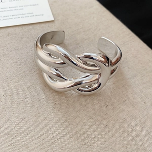 Detailed close-up of a silver knot cuff bracelet featuring a polished metallic finish