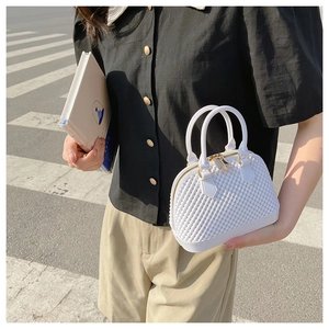 Detail of white PVC jelly bag with woven texture and gold zipper held by a model