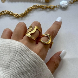 Detail von gestapeltem 18k vergoldetem Wellenring und C-förmigem Band mit glitzernden Strasssteinen