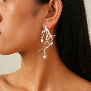 Detailed shot of irregular silver coral-inspired earrings with three elegant white pearls
