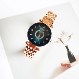 Montre femme quartz or rose avec cadran bleu dégradé et cristaux sur un bureau blanc