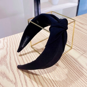 Detail of a handmade black fabric headband with a stylish knot on a gold frame