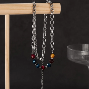 Macro detail of a silver metal chain necklace featuring colorful geometric stone beads