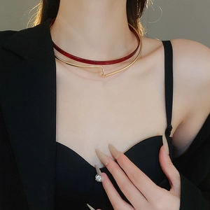 Detail of red resin and gold layered choker necklace worn on a black suit jacket