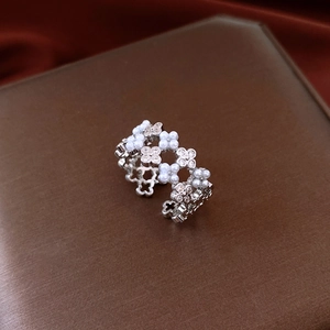 Macro d'une bague trèfle avec perles et zircons sur fond de soie de couleur sombre