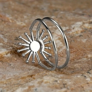 Macro detail of silver double-band sunburst ring on a natural stone background