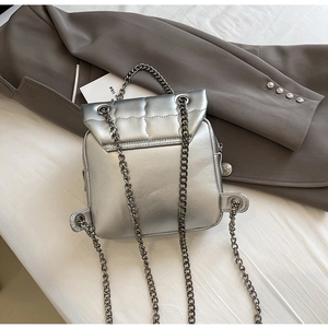 Macro detail of silver quilted metallic backpack with elegant metal chain straps