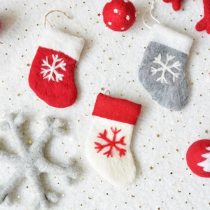 Handmade wool felt Christmas ornaments with stockings, snowflakes and stars on faux fur