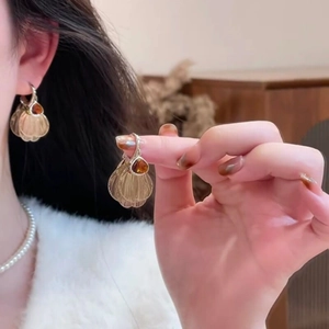 Detailed view of vintage gold shell earrings with amber drop stone and pearl necklace
