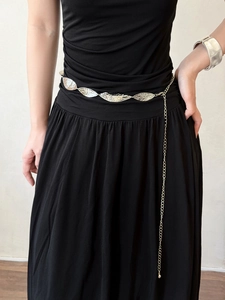 Detail of bohemian silver leaf chain belt styled on a black dress with turquoise accents