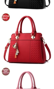 Detail of wine red and rubber red leather handbags with floral tassel and gold hardware