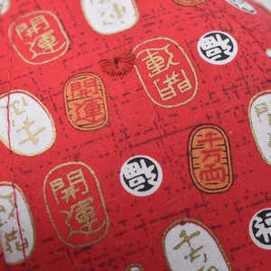 Détail macro de casquette rouge en coton avec œillets brodés et imprimé porte-bonheur