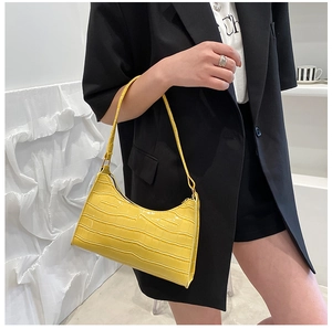 Crocodile pattern embossed bright yellow baguette bag styled as a minimalist underarm handbag