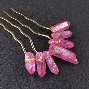 Detail of four handmade pink crystal hair pins with gold wire wrapping on a dark background