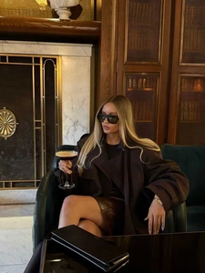 Long trench-coat marron foncé avec ceinture de taille dans un cadre de vie intérieur chic