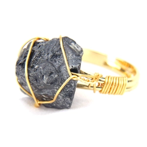 Detailed close-up of handmade gold wire-wrapped raw black agate stone adjustable ring