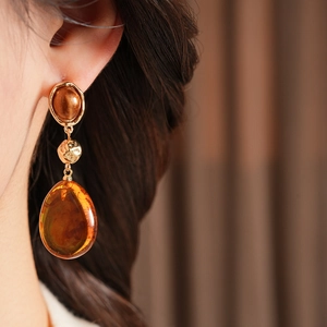 Close-up of retro resin teardrop earrings worn by a model with golden metal details