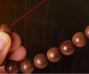 Close-up of natural Phoebe zhennan wood prayer beads showing detailed grain texture