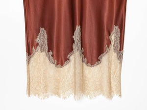 Detailed view of rust red satin skirt hem featuring delicate champagne lace trim