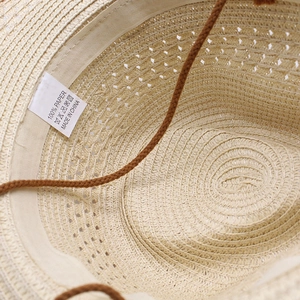 Dettaglio dell'interno del cappello di paglia con etichetta 100% carta e trama intrecciata