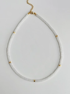 Detail view of white beaded necklace featuring gold spacers and adjustable lobster clasp