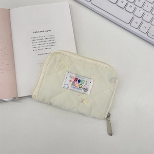 Detailed view of quilted cotton wallet with bow embroidery and secure metal zipper