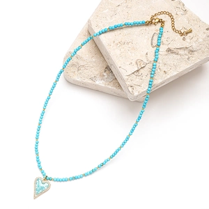 Macro detail of Bohemian beaded necklace featuring a blue heart mosaic pendant