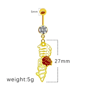 Gros plan du piercing de nombril dore avec zircon et pendentif main de squelette