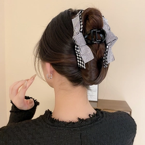 Detail of checkered rhinestone bow hair claw clip securing a long hairstyle with elegance