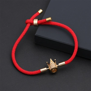 Vue détaillée du bracelet en cordon rouge réglable avec couronne dorée et oxydes de zirconium
