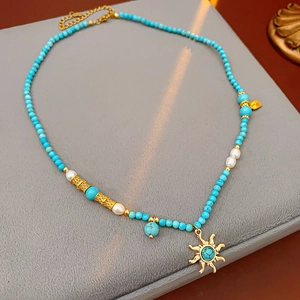 Détail macro du collier pendentif soleil avec perles turquoise et perles d'eau douce